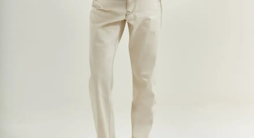 Uomo con giacca marrone e jeans chiari. La vestibilità è slim, non skinny, con risvolti alla caviglia.
