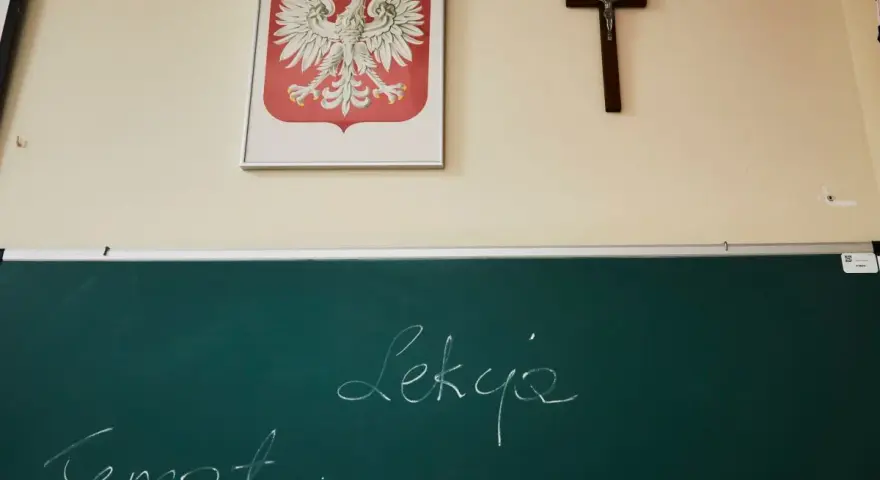 Na ścianie wisi godło Polski i krzyż. Na tablicy napisano "Temat: Lekcja". Czy religia wlicza się do średniej?