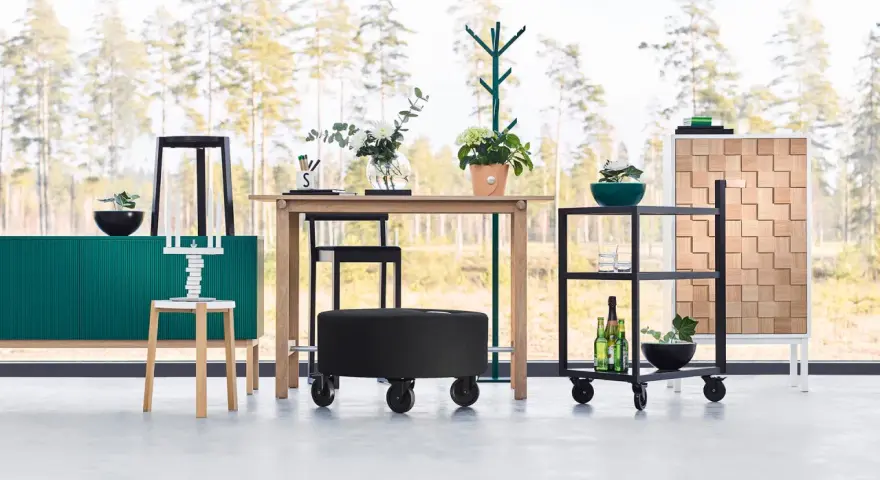 Inredning med en grön skänk, träbord, svarta pallar och en rullvagn. Design från a2 designers.