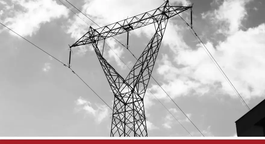 Wysoki słup energetyczny z przewodami, na tle nieba z chmurami. Te linie przesyłowe są kluczowe dla dostarczania energii.