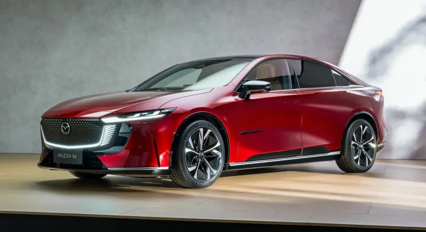 Elegancka, czerwona mazda elektryczna z nowoczesnym designem, prezentowana na drewnianej scenie.