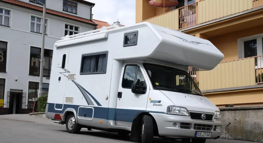 Biały kamper Fiat Ducato zaparkowany na ulicy. Zastanawiasz się, ile miejsc ma bus tego typu?