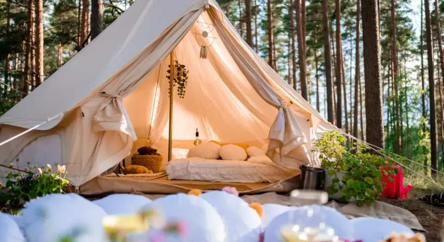 Przytulny namiot w lesie, idealny na glamping w Polsce. Wygodne łóżko, dekoracje i otoczenie natury tworzą magiczną atmosferę.