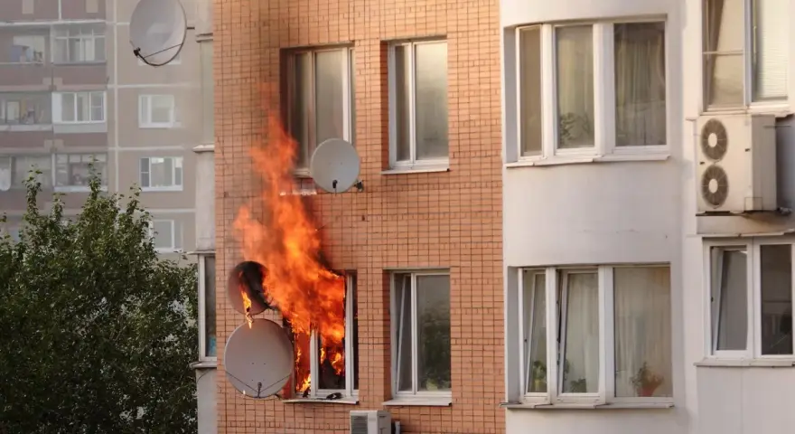 Flammen schlagen aus einem Fenster eines Mehrfamilienhauses. Ein trauriger Anblick, besonders wenn man bedenkt, dass es sich um einen wohnungsbrand ohne hausratversicherung handelt.