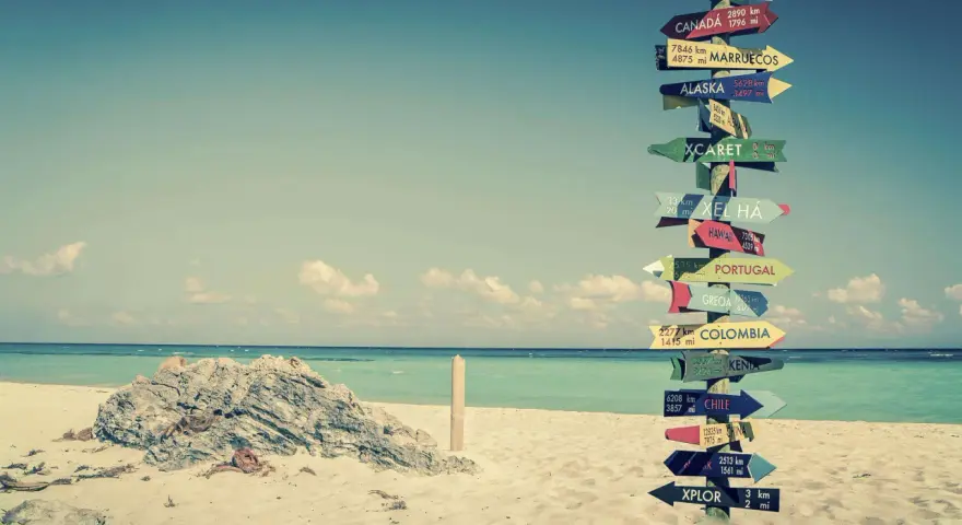 Strand mit Schildern zu fernen Zielen. Ein Traum für ein **auslandsjahr kostenlos**?