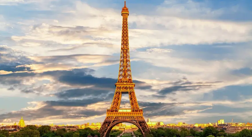 Le symbole de la Tour Eiffel se dresse fièrement sous un ciel nuageux, illuminé par les rayons du soleil couchant.