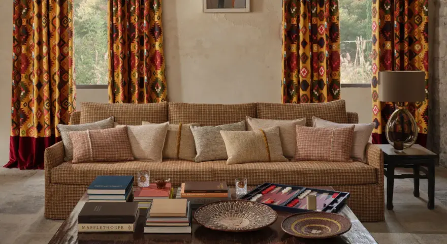 Cortinas con estampado geométrico vibrante, un sofá acogedor y cojines texturizados. Las ultimas tendencias cortinas salon se reflejan en este espacio.