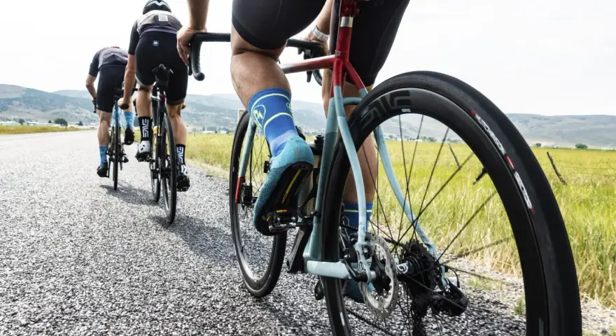 Cyclists on an endurance bike vs road bike race down a gravel road, showcasing their gear and determination.