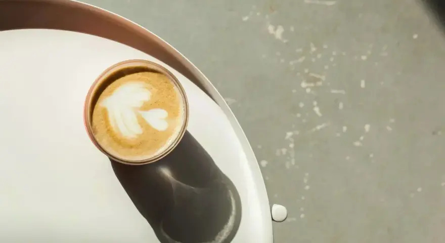 Idealna kawa flat white z pianką w kształcie liścia, podana na tacy.