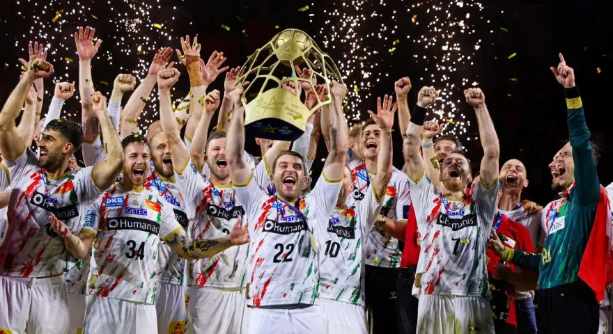 Drużyna świętuje zwycięstwo w finale piłki ręcznej, unosząc puchar. Konfetti i fajerwerki podkreślają radość.