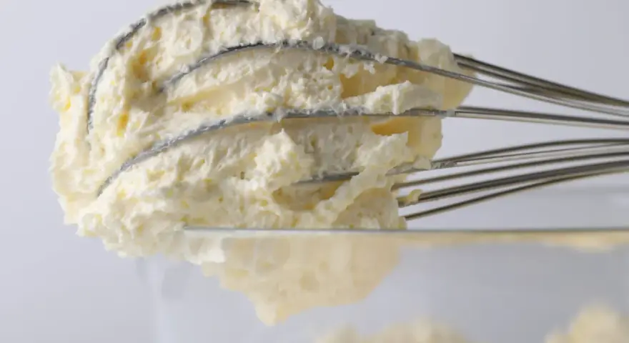 Puszysty krem z mascarpone, ubijany na drucianych trzepaczkach miksera, gotowy do deseru.