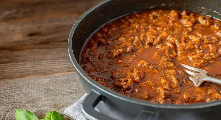Un saporito ragù di anatra, ricetta veneta, pronto in padella con una forchetta. Profumo di basilico fresco.