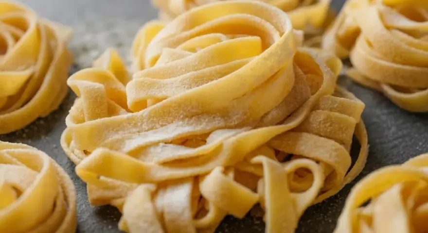 Nidi di tagliatelle fatte in casa, spolverate di farina, pronte per essere cucinate.