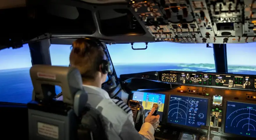 Pilota in cabina di pilotaggio, con schermi e comandi. Chissà quanto guadagna un pilota di aerei per gestire un volo così complesso.