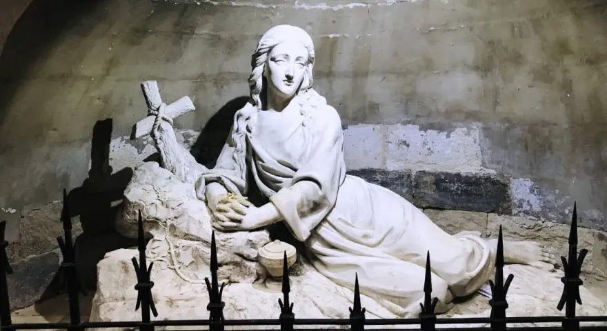 Sculpture of Mary Magdalene in repose, near a cross, possibly at her burial site.