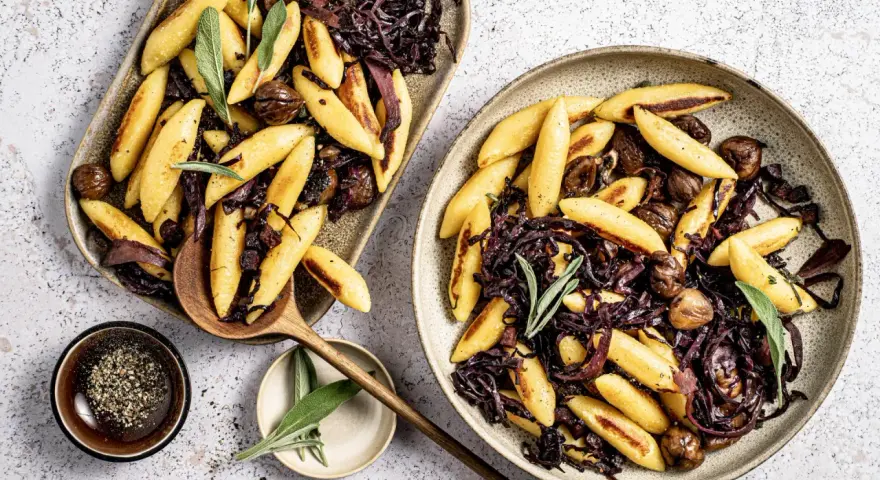 Schupfnudeln mit Rotkohl und Kastanien, garniert mit Salbei. Ein herzhaftes Gericht, das zum Genießen einlädt.