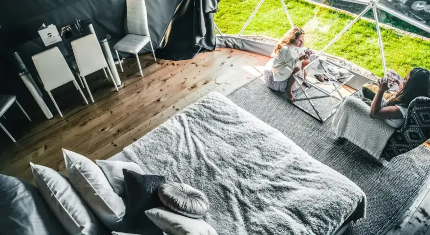 Dwie kobiety relaksują się w luksusowym namiocie. Przytulne wnętrze z wygodnym łóżkiem i stolikiem kawowym, idealne na camping w Zakopanem.