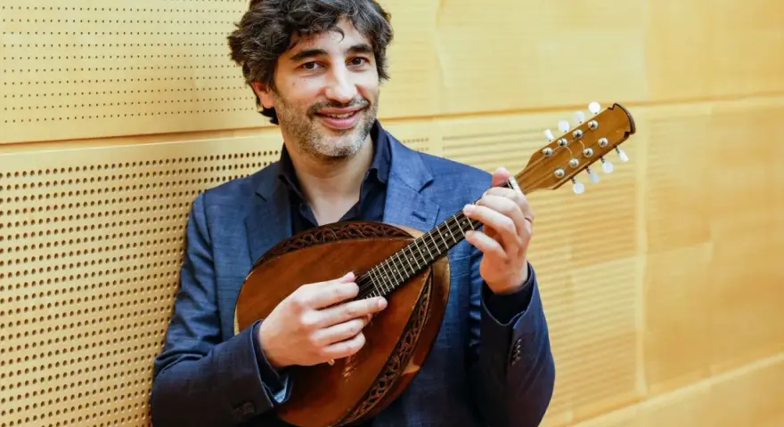 Mann mit Mandoline, die acht Saiten hat, lächelt.