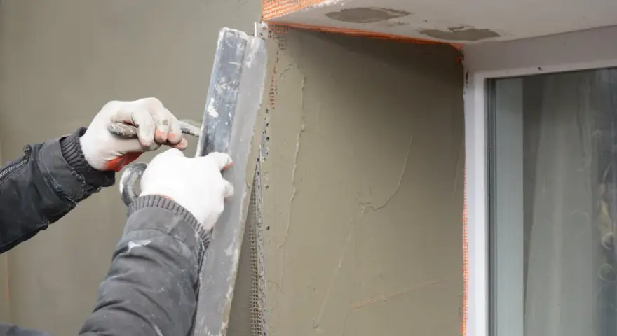 Lavori di intonacatura attorno alle spallette delle finestre, con un operaio che stende il materiale.