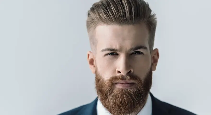 Mężczyzna z gęstą, rudą brodą, prezentujący jeden z popularnych rodzajów brody. Elegancki styl i zadbanie.