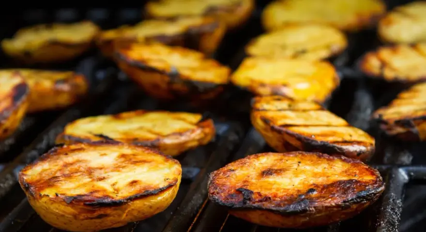 Patate alla griglia dorate e succulente, con segni di cottura perfetti, pronte per essere gustate.