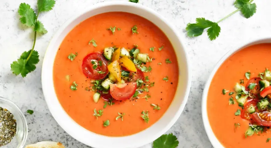 Två skålar med uppfriskande gazpacho, toppad med färska grönsaker. Ett perfekt gazpacho recept för varma dagar.