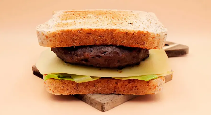 Burger z wołowiny, serem, sałatą i tostami na desce.