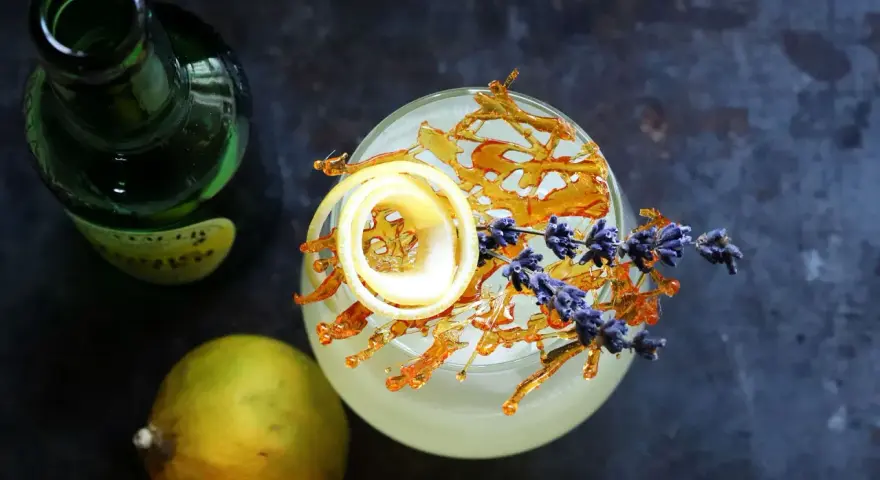 Erfrischender Drink mit Zitronenzeste, Karamell und Lavendel. Die bergamotte verwendung in Cocktails ist ein Genuss.