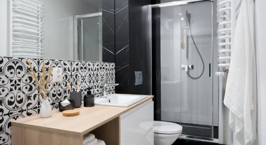 Élégante petite salle de bain italienne avec carrelage noir et blanc, douche moderne et meuble vasque en bois clair.