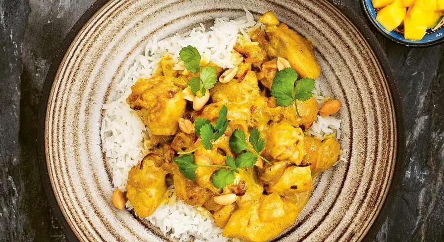 En krämig kycklingcurry med ris, toppad med koriander och jordnötter. En riktig curry nam nam!