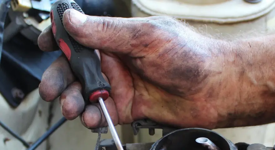 Brudna ręka mechanika z kluczem, naprawia coś w samochodzie. Może to być związane z linki skrzyni biegów objawy.