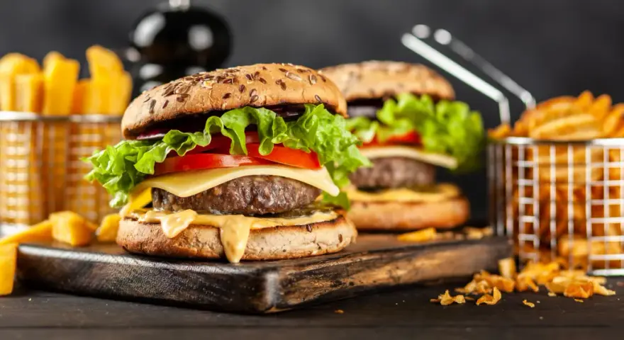 Dwa soczyste hamburgery z serem, sałatą i pomidorem, podane z frytkami.