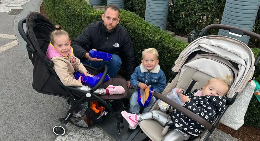 Familie genießt Snacks, um Disneyland Paris Essen mitzunehmen. Kinder in Kinderwagen und Vater mit Boxen.