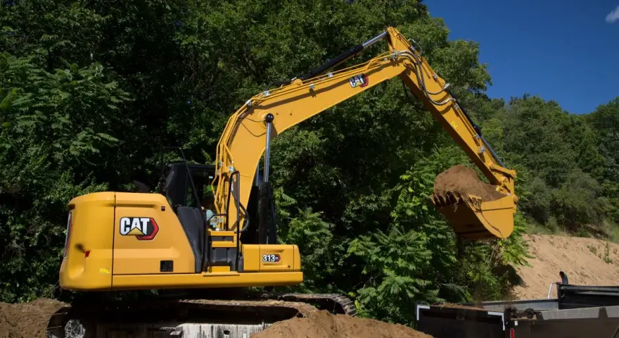Żółta koparka Cat 313 z łyżką pełną ziemi, gotowa do pracy. Dane techniczne tej maszyny budowlanej są imponujące.