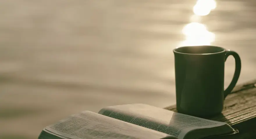 Offenes Buch mit Bibelversen, Tasse Kaffee am Seeufer. "Ich liebe den Herrn, denn er hört meine Stimme" (Psalm 116:11).