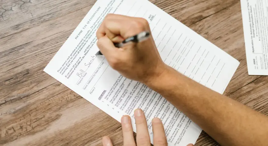 Osoba wypełnia formularz podatkowy, wpisując dane. Pytania dotyczą rezydencji podatkowej i dochodów.