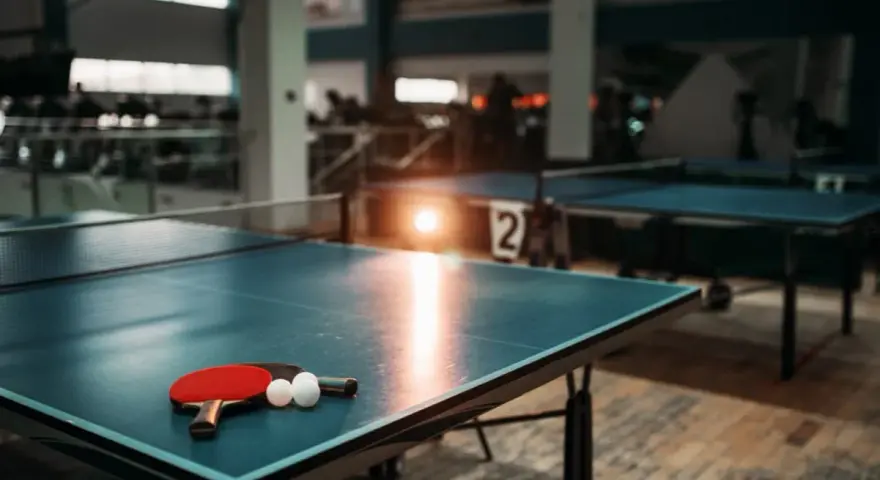 Tischtennisplatten in Berlin, bereit für das nächste Match. Ein roter Schläger und zwei weiße Bälle liegen auf dem blauen Tisch.