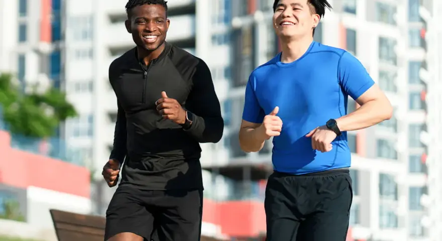 Deux hommes souriants courent ensemble dans un parc, profitant de leur routine pour courir tous les jours.