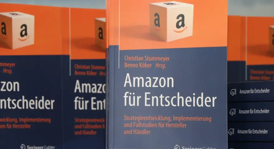 Bücher "Amazon für Entscheider" mit Amazon-Logo-Würfel im Vordergrund.