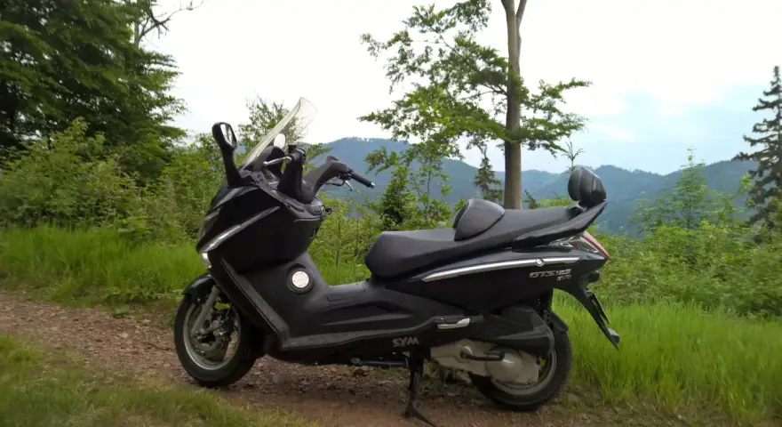Czarny skuter Sym GTS 125 na górskiej drodze. Jego prędkość maksymalna pozwala na odkrywanie malowniczych zakątków.