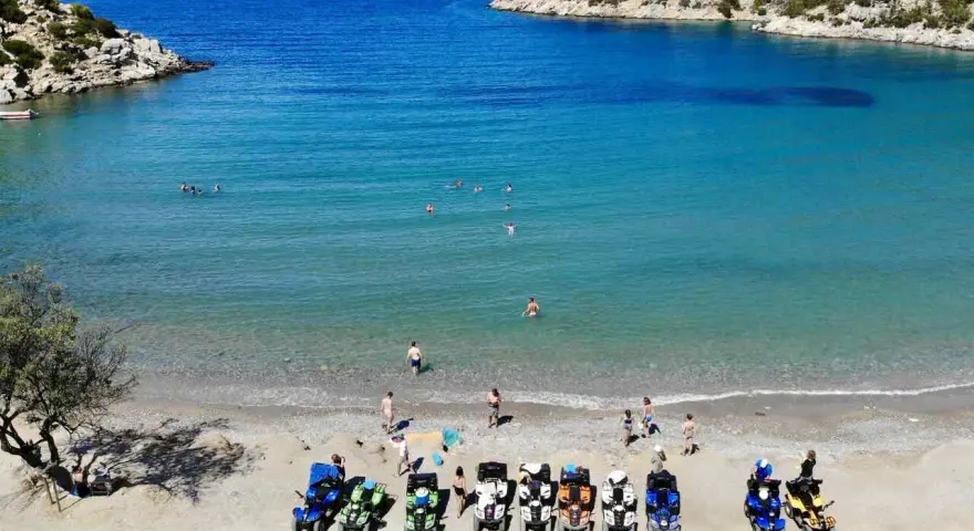 Linia pojazdów terenowych na plaży w Poros, Grecja, czeka na chętnych do zwiedzania. W tle turkusowe morze i skaliste wybrzeże.