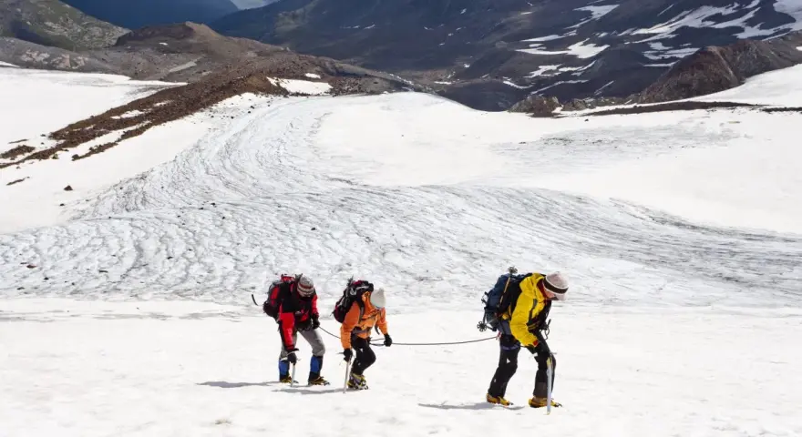 Drei Bergsteiger seilen sich über einen eisigen Gletscher in den Alpen ab.