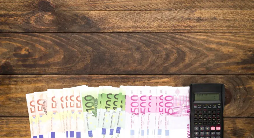 Banknoty euro i kalkulator na drewnianym tle.