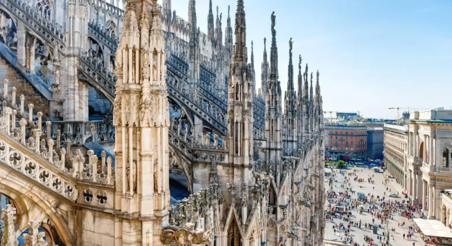 Majestatyczne iglice katedry Duomo w Mediolanie w listopadzie, z widokiem na tętniący życiem plac poniżej.