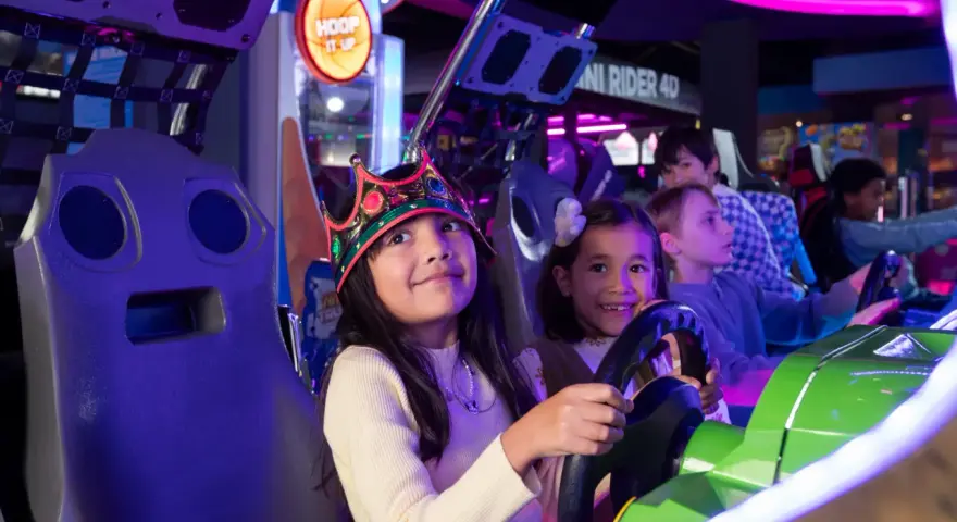Kinder mit Kronen auf dem Kopf spielen in einer Spielhalle in Berlin Rennspiele.