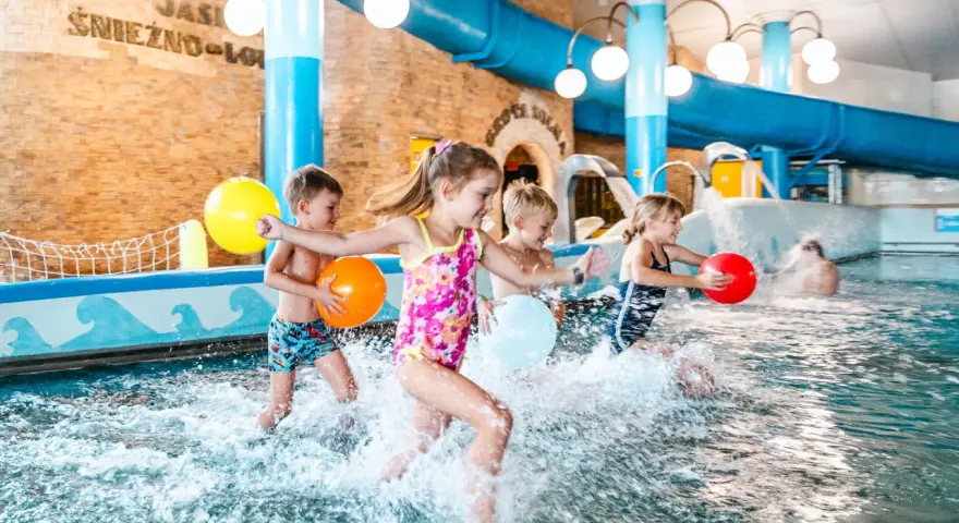 Dzieci bawią się w basenie, rzucając kolorowymi piłkami. Idealne miejsce na rodzinny wypoczynek - hotel z basenem dla dzieci Podlaskie.