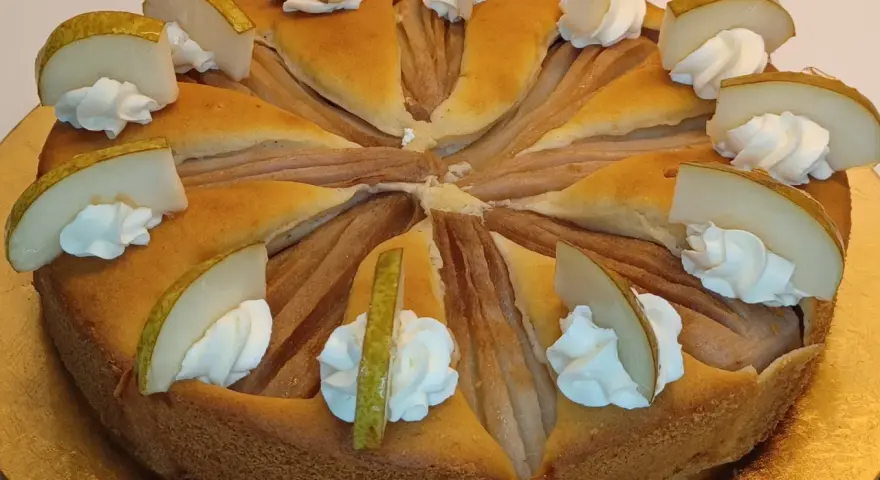 Ein köstlicher Birnenkuchen, verziert mit Sahnetupfern und frischen Birnenspalten. Perfekt für ein Birnenkuchen Rezept.