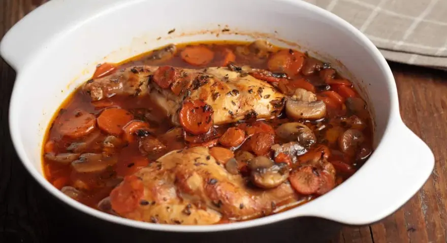 Conejo en cazuela con zanahorias y champiñones en salsa roja.