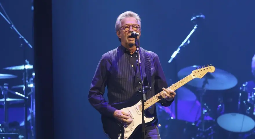 Eric Clapton gra na gitarze, wykonując swoje legendarne utwory.