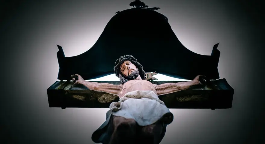 A statue of Jesus on the cross, with a dark canopy above. This image evokes the sacrifice and the question of why Jesus died.